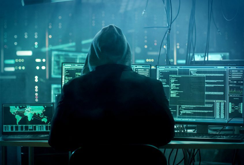 Dangerous Hooded Hacker Breaks into Government Data Servers and Infects Their System with a Virus. His Hideout Place has Dark Atmosphere, Multiple Displays, Cables Everywhere.